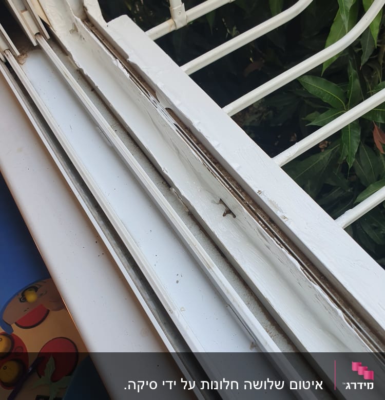 חלון עם איטום לבן מתקלף ומסגרת מתכת